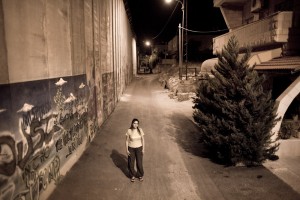 Claire Anastas between the wall built by the Israeli government and its housing